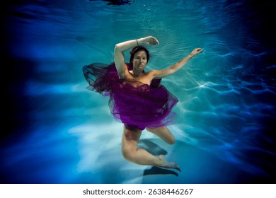 wearing in a violet dress lass is undersea in the swimming pool