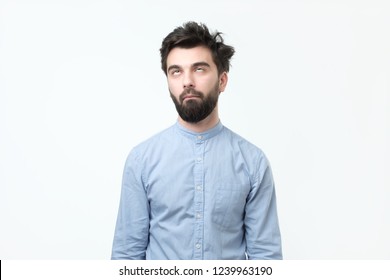 Weary hispanic man in blue shirt rolling his eyes up. He is exhausted with work or tired of listening his wife chatting.