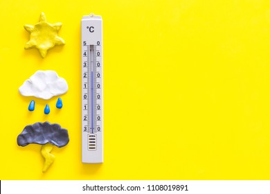 Weather Forecast Concept. Air Temperature. Termometer Among Cloud And Lightening, Sun, Rainy Clouds On Yellow Background Top View Copy Space