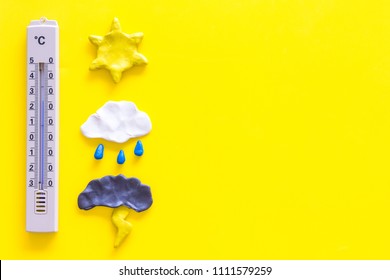 Weather Forecast Concept. Air Temperature. Termometer Among Cloud And Lightening, Sun, Rainy Clouds On Yellow Background Top View Copy Space