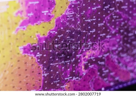 A weather forecast map on a screen displays extreme heatwave temperatures over France and Western Europe, with deep purple colors and numbers reaching 50 degrees Celsius, symbolizing global warming.