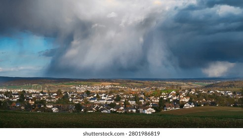 Weather scenery with dramatic rain clouds over a scenic village. Dark rainclouds over the horizon of a rural countryside.