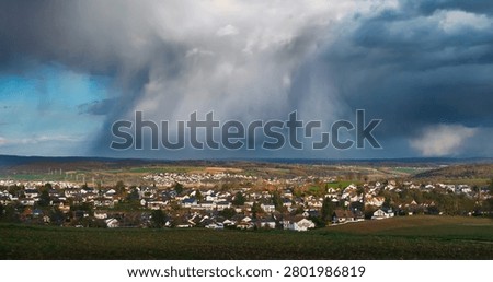 Weather scenery with dramatic rain clouds over a scenic village. Dark rainclouds over the horizon of a rural countryside.