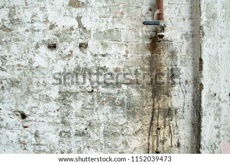 weathered abandoned grunge wall with old antique water tap and pipes 