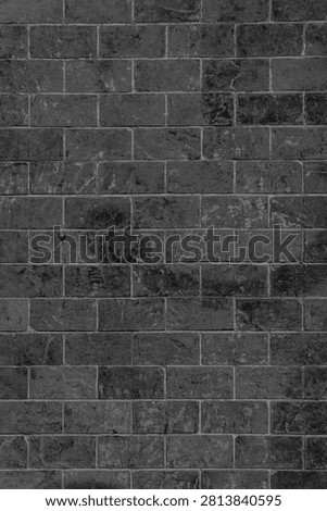 Weathered anthracite stone wall with vertical block layouts and visible lime traces. Distressed charcoal masonry facade with scratches and mineral stains for a dark industrial background.