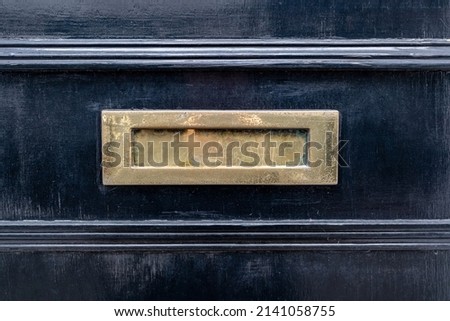 Weathered brass letterbox in a black victorian door