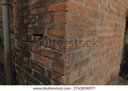 Weathered brick structural corner wall of a humble dwelling showing deteriorated masonry mortar lines captured with raw macro textures and deep directional shadows in Birbhum West Bengal for systemic poverty and marginalization concepts.