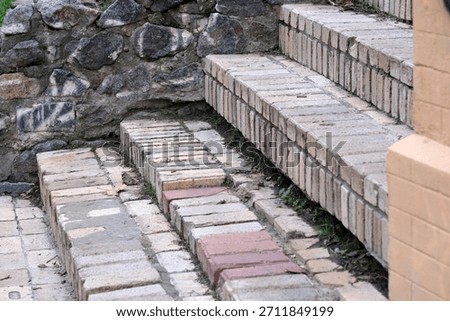 Weathered bricks form charming steps, surrounded by rugged stone and greenery.