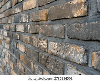 Weathered bricks form a textured wall, showcasing visible mortar lines and varying shades of red and brown. Vertical composition captures roughness and detail of aged bricks, perfect for rustic