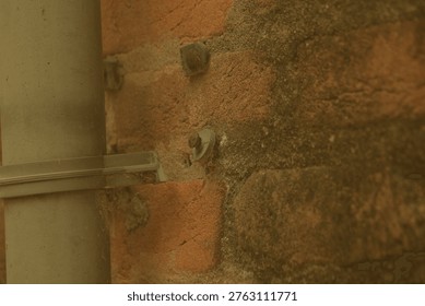 Weathered brickwork structure adjacent to a plain metal structural column in Birbhum West Bengal under muted light showcasing directional shadows and raw macro textures that suggest systemic poverty and economic crisis balanced by persistent local dignity for texture and transition concepts.
