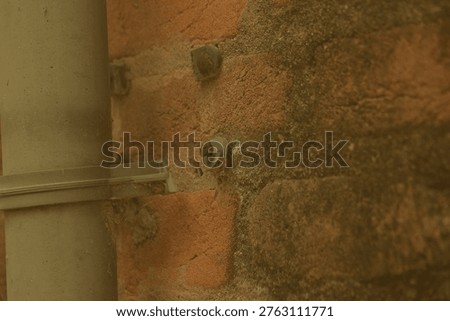 Weathered brickwork structure adjacent to a plain metal structural column in Birbhum West Bengal under muted light showcasing directional shadows and raw macro textures that suggest systemic poverty and economic crisis balanced by persistent local dignity for texture and transition concepts.
