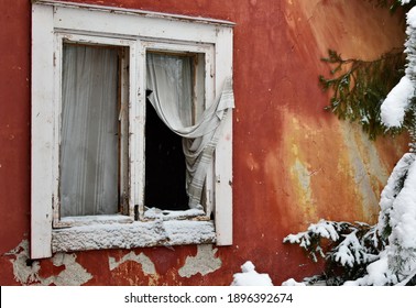 Weathered Broken Window Of An Abandoned House With A Colorful Wall. Snowy Trees And Window Panes.