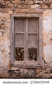 Weathered broken window in deteriorating stone wall on Spinalonga fortress island, Crete Greece. Historic abandoned building architectural decay.