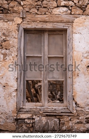 Weathered broken window in deteriorating stone wall on Spinalonga fortress island, Crete Greece. Historic abandoned building architectural decay.