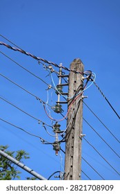 Weathered concrete utility pole with multiple electrical wires and glass insulators against a clear blue sky