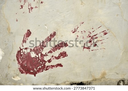A weathered concrete wall featuring a cryptic red handprint and smeared markings