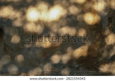 Weathered concrete wall texture with warm glowing light spots, distressed details and earthy tones, creating an atmospheric vintage industrial background. 