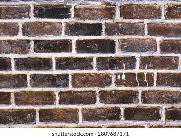 Weathered dark brick wall texture with aged masonry, vintage surface and rustic architectural background for design and construction
