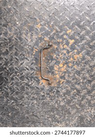 Weathered diamond pattern steel panel with corroded pull handle and chipped paint, rugged non slip tread texture background for industrial safety signage and repair themes