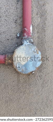 Weathered Electrical Junction Box with Red Conduit on Concrete Wall