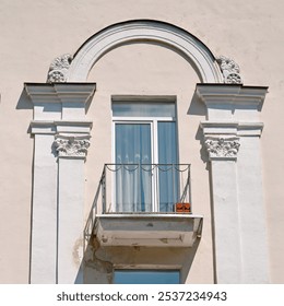 Weathered facade of historic building with detailed arch, distressed balcony, and signs of structural damage, need for facade restoration works. Pilasters and decorative arch with window and balcony - Powered by Shutterstock