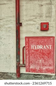 Weathered fire hydrant box. Dirty wall in the back.