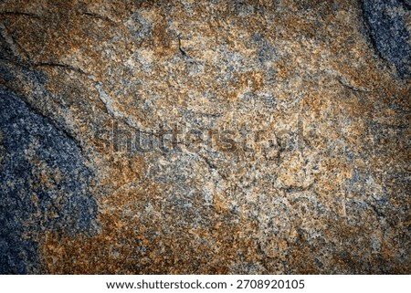 Weathered granite rock texture. Close-up of rough natural stone surface with blue, gray and rusty orange flecks. Abstract rocky background for design, printing and 3D visualization.