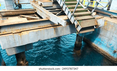 a weathered, green metal staircase leading down to a pier over clear blue water - Powered by Shutterstock