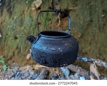 A Weathered Kettle Hanging Over a Rustic Fire Pit