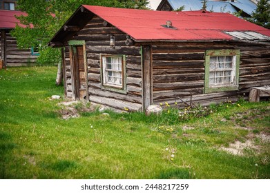 Weathered log cabin, indicative of colorado's rich history, stands in a mountainous landscape, representing the enduring spirit of the heart land's nature - Powered by Shutterstock