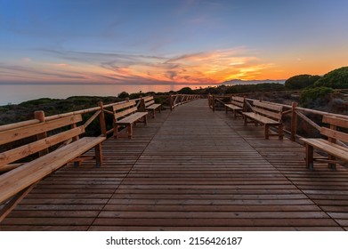 Weathered lumber path leading to calm sea during beautiful sunset in countryside in Cabopino, Artola dunes. Marbella, Spain
