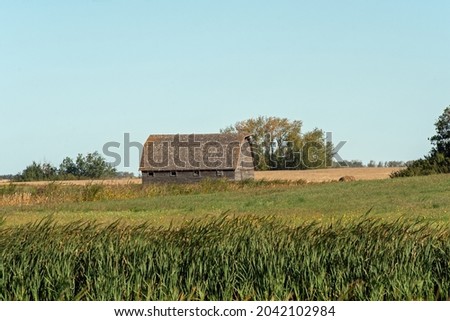 A weathered old barn, abandoned in a field of an old farm yard in rural Saskatchewan in the Canadian prairies.