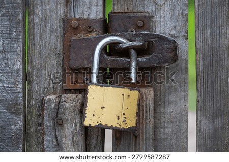 A weathered padlock secures a latch on an old, rough-hewn wooden door