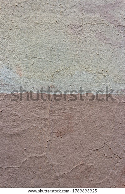 Weathered and peeling building exterior stucco wall\
painted white and salmon pink. Wall Painted Two Tone. The wall is\
divided into borders of different colors. Abstract geometric\
pattern on the wall.
