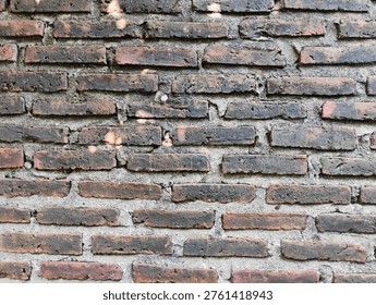 ​Old weathered red brick wall texture background with rough cement joints and vintage rustic feel.