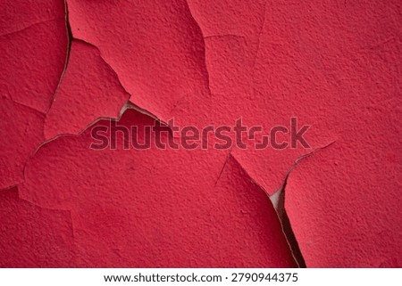 Weathered red painted wall featuring natural cracks and distressed texture, perfect for creative backgrounds and graphic design