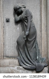 A Weathered Relief Of A Grieving Mother In Front Of A Crypt.