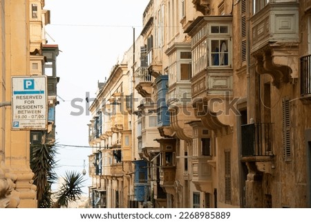 Weathered residential limestone building facades with traditional wooden balconies in Malta's capital city