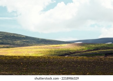 Weathered rugged moss hill mountain with sunlight and blue sky on summer in Icelandic highlands at Iceland