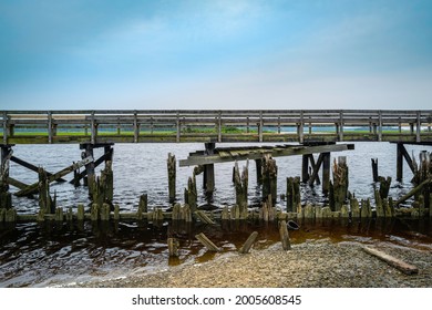 Weathered Ruined Wooden Dock At Shore In Scituate, Massachusetts. Historic Seascape In American New England Landscape. Abstract Geometry Of Horizontal Architecture On Blue Sky And Sea Backdrop. 