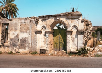 weathered ruins of a historical building with a green wooden door under the bright sun - Powered by Shutterstock