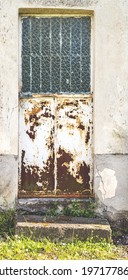 Weathered And Rusty Metal Door With Frosted Glass Window In Old House Facade,vertical Wide Shot