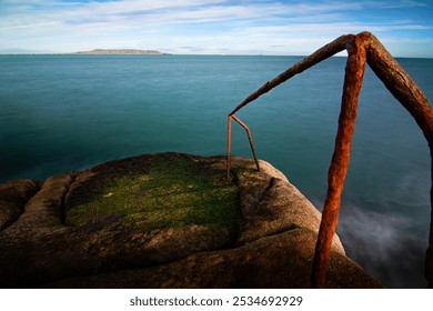 A weathered and rusty metal railing gently leads down toward the vast expanse of the ocean, inviting a sense of adventure and tranquility - Powered by Shutterstock