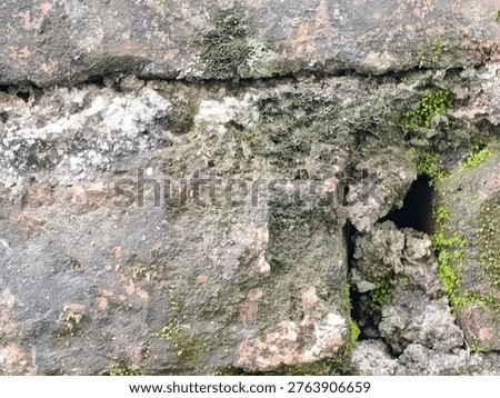 Weathered stone blocks with rough texture, patches of moss, and visible cracks, showing signs of age and natural wear.