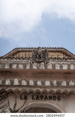 Weathered stone eagle statue perched on the roof of a classic building with the text La Lavande.