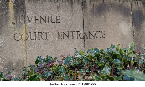 Weathered stone slab sign with the words juvenile Court Entrance engraved into it with foliage at the bottom Outside the Department Of Justice courthouse where juveniles are tried.  - Shutterstock ID 2012981999
