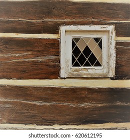 Weathered texture of small square lead glass window on old rustic wooden house, with sepia tone 