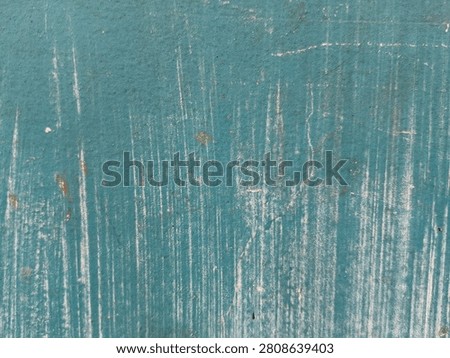 weathered turquoise plaster wall showcasing white vertical chalky brush streaks and scratch marks.