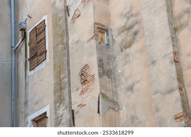 A weathered wall in Zadar Croatia, plaster is rotten and bricks are visible. window with weathered shutters, small window with curtains. - Powered by Shutterstock