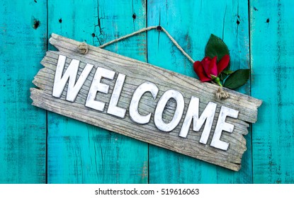 Weathered Welcome Sign With Red Flower Hanging On Antique Rustic Teal Blue Wood Door; Holiday Background With Home Concept